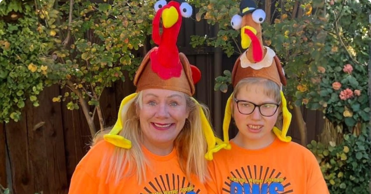 Woman and young person wearing turkey hats and orange PWS shirts outdoors.