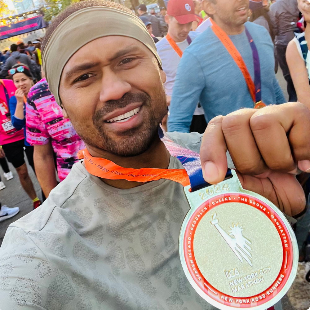 Team FPWR runner smiling and holding his 2024 New York City Marathon medal.