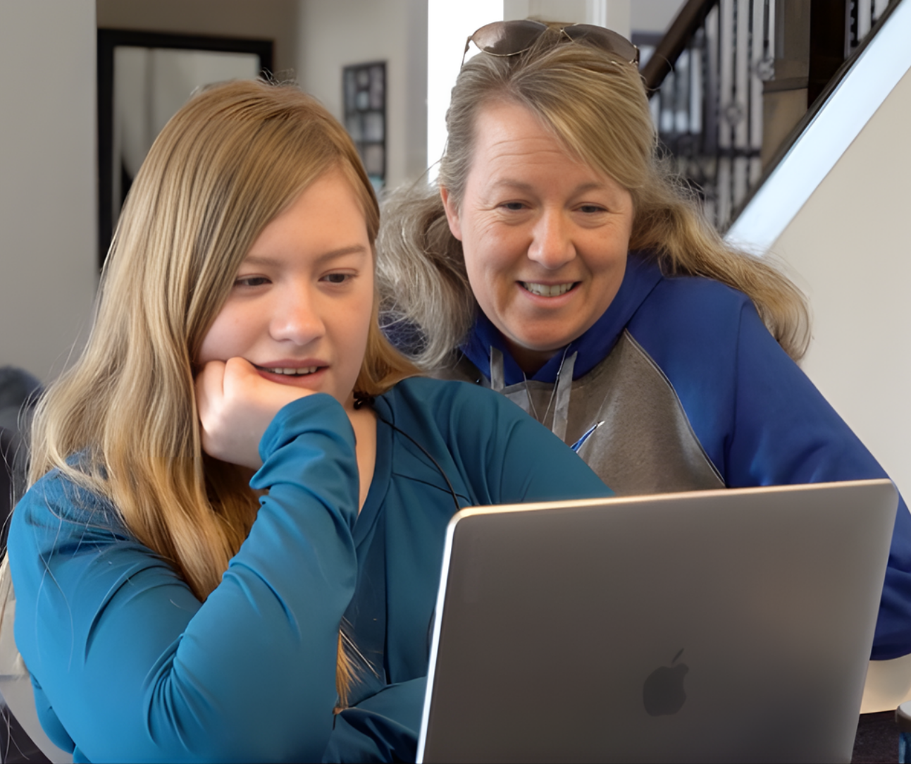 Young woman and older woman smiling as they look at a laptop together.